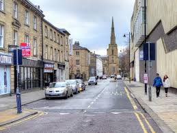 a photograph of a street in Huddersfield town centre with a church in the background cars in the foreground - where stabbings in West Yorkshire occurred